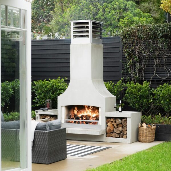 Full-height outdoor fireplace against a dark slatted fence, giving a flat courtyard vertical interest