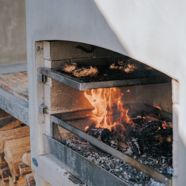 Close-up of food grilling over the fire in a Flare outdoor fireplace.