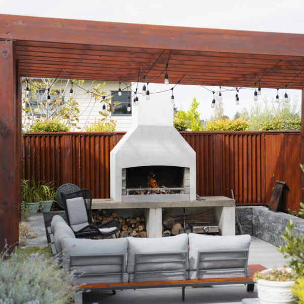 Modular lounge seating arranged in an arc around an outdoor fireplace, under string lights