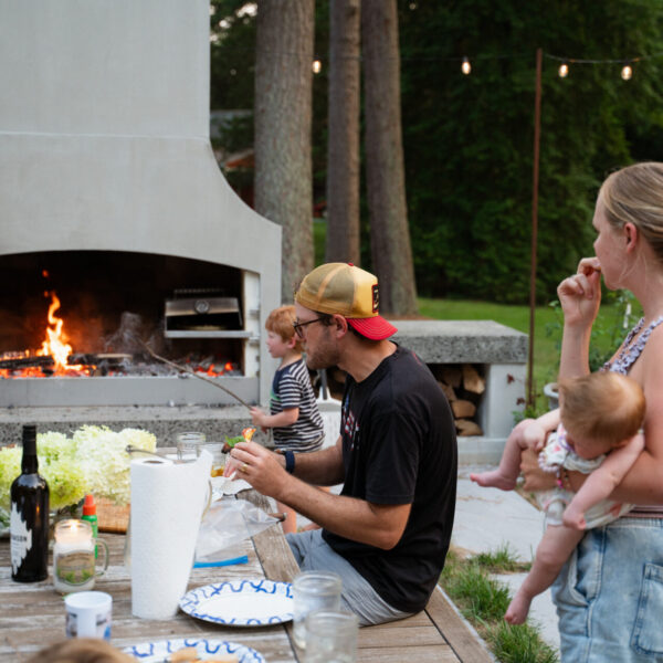 Family cooking on a Flare outdoor fireplace on a summer evening.